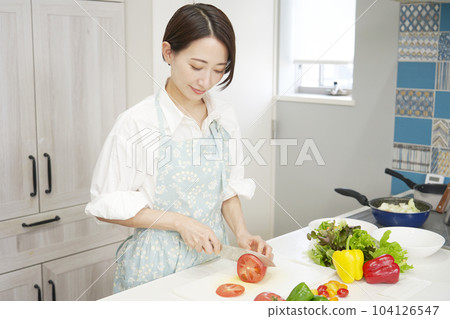 Middle aged woman cutting tomatoes in the kitchen Middle aged woman cutting tomatoes in the kitchen 104126547