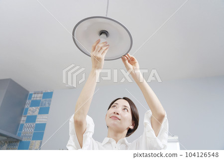 Woman exchanging light bulbs 104126548