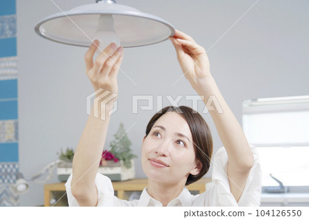 Woman exchanging light bulbs 104126550