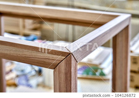 Wooden frame of bedside table made of solid walnut in workshop. Joinery angular joint of planks on dowels closeup Wooden frame of bedside table made of solid walnut in workshop. Joinery angular joint of planks on dowels closeup 104126872