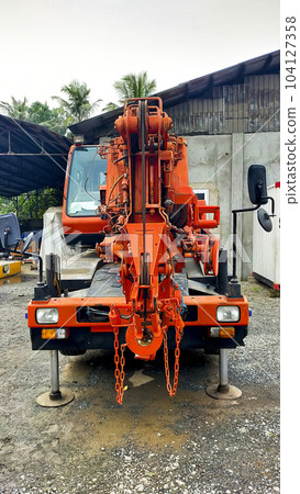 Front view of orange small city crane or CTC jacking up and parking. Front view of orange small city crane or CTC jacking up and parking. 104127358