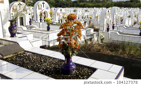 Tombstone and flowers in a vase on a white ceramic grave in cemetery or graveyard. Tombstone and flowers in a vase on a white ceramic grave in cemetery or graveyard. 104127378