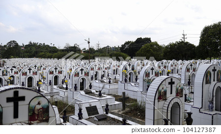 The public cemetery contains identical white ceramic graves with flowers. 104127387