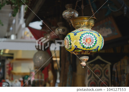 Market with handmade traditional colorful Turkish lamps and lanterns, selective focus on lantern, blurred background, popular souvenir lanterns hanging in shop for sale. Market with handmade traditional colorful Turkish lamps and lanterns, selective focus on lantern, blurred background, popular souvenir lanterns hanging in shop for sale. 104127553