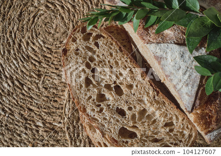 Slicing artisan bread on a straw lining, top view. Pieces of fresh homemade sourdough bread, healthy healthy cuisine Slicing artisan bread on a straw lining, top view. Pieces of fresh homemade sourdough bread, healthy healthy cuisine 104127607