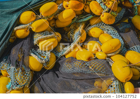 Fishing nets with yellow floats on the pier, close-up, selective focus. Background for industrial fishing concept 104127752
