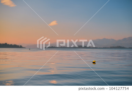 Gorgeous sunset sky over the sea, selective focus on the yellow buoy. Silhouettes of a number of islands and mountains on the horizon. Idea for backgrounds or screens. Beauty of nature, vacation time Gorgeous sunset sky over the sea, selective focus on the yellow buoy. Silhouettes of a number of islands and mountains on the horizon. Idea for backgrounds or screens. Beauty of nature, vacation time 104127754