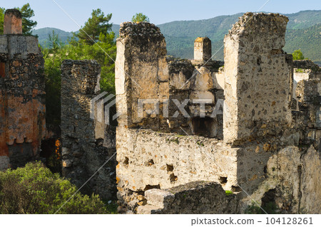 ruins of the abandoned Greek city of Levissi near the village of Kayakoy in Fethiye Turkey, against the backdrop of cumulus clouds, the tragedy of wars. Site of the ancient city of Karmilissos 104128261