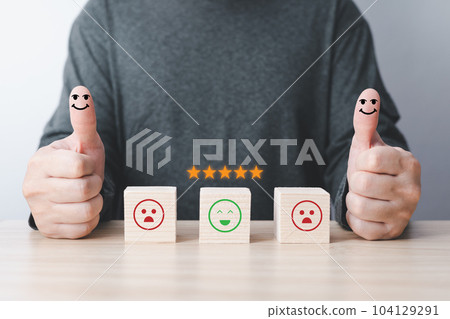 businessman thumbs up on the happy smiling face and five stars icon on the wood block square to give satisfaction in service. rating very impressed.Customer service evaluation and Satisfaction concept 104129291