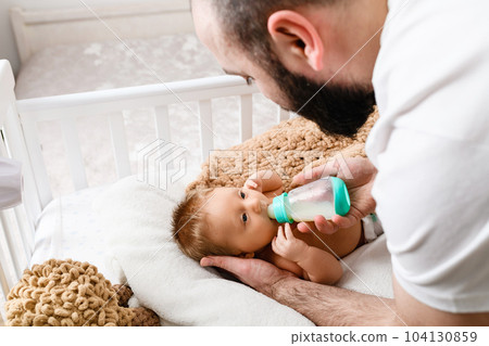 Father feed sleepy infant with baby formula 104130859