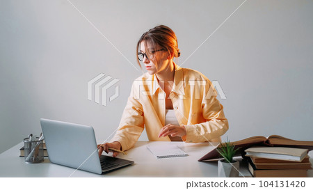 Online job. Laptop browsing. Network search. Concentrated woman freelancer working distance education using computer sitting at table against gray wall with copy space. 104131420