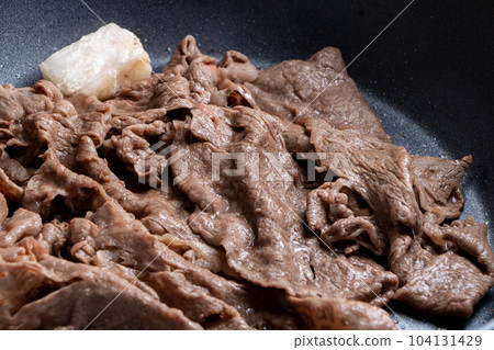 A cooking scene where beef (thinly sliced) is baked in a frying pan. 104131429