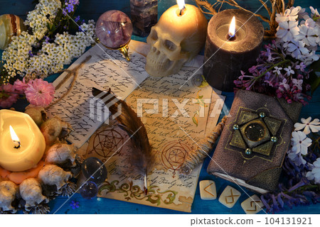 Candles, runes and manuscript with spell on witch ritual table. Occult, esoteric and fortune telling still life. Mystic background with vintage objects 104131921