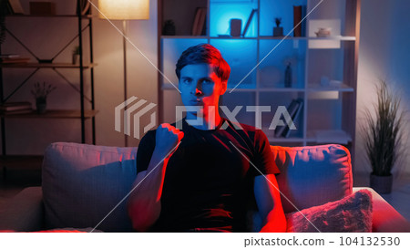 Yes gesture. Powerful man. Successful achievement. Confident guy holding hand up with fist with facial expression in dark neon light home interior. Yes gesture. Powerful man. Successful achievement. Confident guy holding hand up with fist with facial expression in dark neon light home interior. 104132530