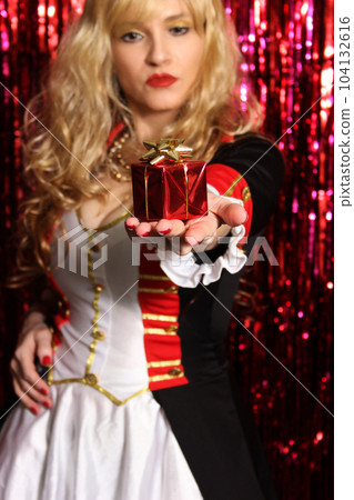 Blonde Woman Wearing Toy Soldier Costume and Holding Christmas Gift in Hand Blonde Woman Wearing Toy Soldier Costume and Holding Christmas Gift in Hand 104132616