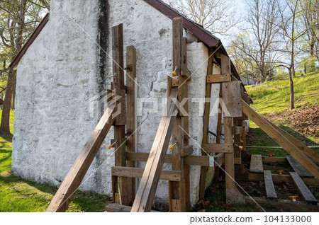 Wooden support scaffolding braces cracked wall of colonial cottage Wooden support scaffolding braces cracked wall of colonial cottage 104133000