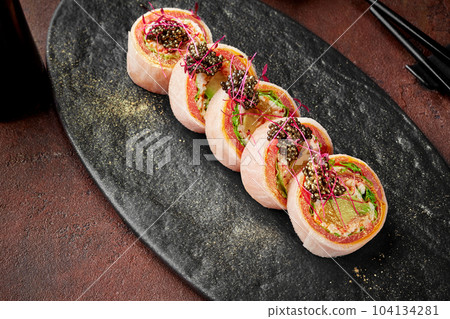 Sushi rolls with tuna, omelette, lettuce, avocado, orange, black tobiko 104134281