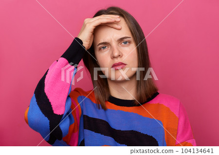 Photo of sick tired unhealthy woman wearing colorful jumper, suffering headache, touch her painful head, having flu symptoms, posing isolated over pink background. 104134641