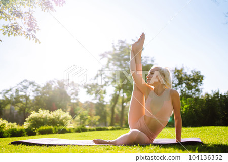 Young woman doing excercise at the public park. Fitness woman doing yoga exercises in the morning. Young woman doing excercise at the public park. Fitness woman doing yoga exercises in the morning. 104136352