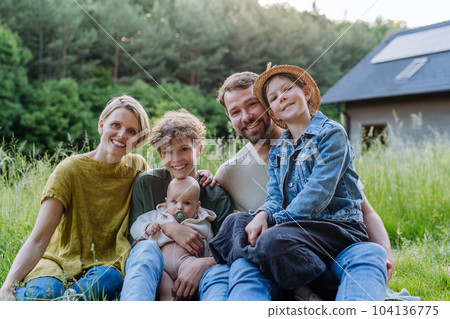Happy family near their house with solar panels. Alternative energy, saving resources and sustainable lifestyle concept. 104136775