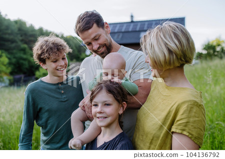 Happy family near their house with solar panels. Alternative energy, saving resources and sustainable lifestyle concept. Happy family near their house with solar panels. Alternative energy, saving resources and sustainable lifestyle concept. 104136792