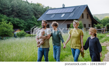 Happy family near their house with solar panels. Alternative energy, saving resources and sustainable lifestyle concept. 104136807