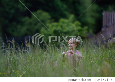 Happy boy playing and running on a meadow. 104137127