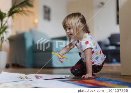 Cute little girl drawing with crayons, sitting on the floor at home. Cute little girl drawing with crayons, sitting on the floor at home. 104137266