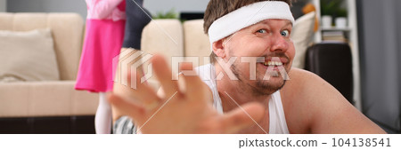 Laughing little girl pulling dad leg on floor 104138541