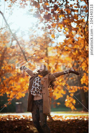 happy elegant woman in beige coat and orange hat rejoicing 104140318