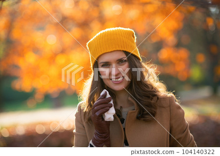 smiling stylish woman in beige coat and orange hat 104140322