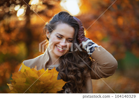 smiling young woman in beige coat and orange hat smiling young woman in beige coat and orange hat 104140329