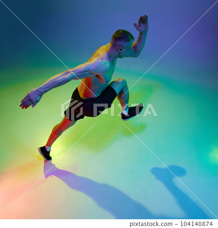 Sport achievements. Top view image of man, professional runner, athlete in motion against gradient studio background in neon light Sport achievements. Top view image of man, professional runner, athlete in motion against gradient studio background in neon light 104140874