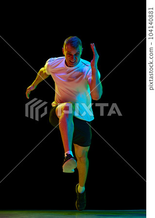 Front view image of handsome, muscular man, professional athlete in motion, running against white studio background 104140881
