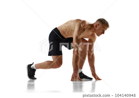 Ready, steady, go. Muscular man, professional athlete, runner standing in position to start running against white studio background 104140948