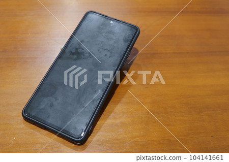 A dirty smartphone left on the table in a restaurant. A dirty smartphone left on the table in a restaurant. 104141661