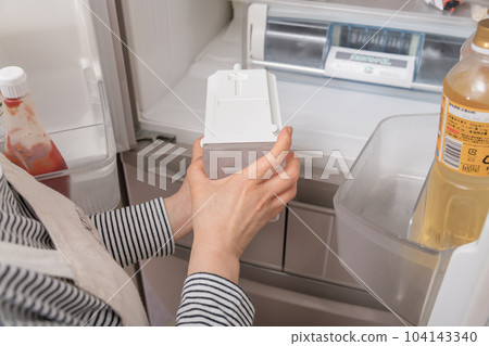 [Housewife taking out the water tank from the refrigerator] 104143340