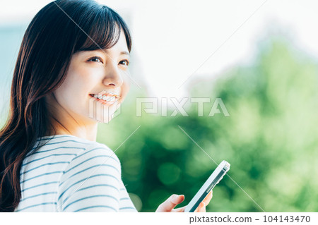 操作智能手機的年輕女子。 操作智能手機的年輕女子。 104143470
