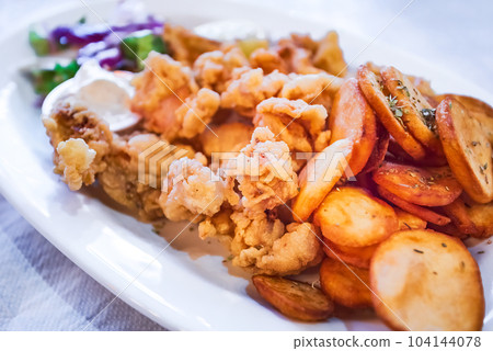 Classic greek taverna plate with fried calamari and baked potatoes, seafood. Classic greek taverna plate with fried calamari and baked potatoes, seafood. 104144078