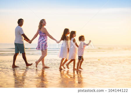 Family walking on tropical beach at sunset 104144122
