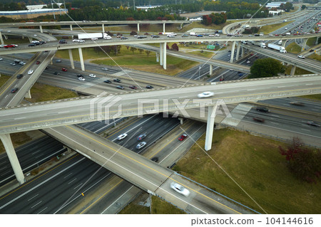 American freeway intersection with fast driving cars and trucks. View from above of USA transportation infrastructure American freeway intersection with fast driving cars and trucks. View from above of USA transportation infrastructure 104144616