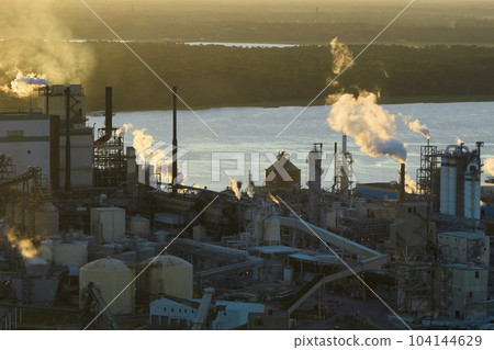Aerial view of wood processing factory with smoke from production process polluting atmosphere at plant manufacturing yard. Industrial site at sunset 104144629