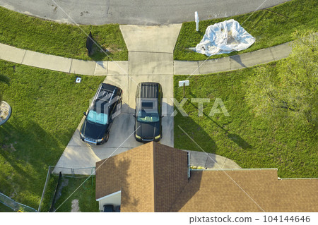 Aerial view of typical contemporary american private house with roof top covered with asphalt shingles and green lawn on yard 104144646