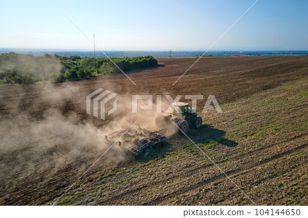 Aerial view of tractor plowing agriculural farm field preparing soil for seeding in summer 104144650