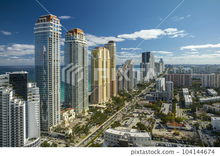 Aerial view of Sunny Isles Beach city with luxurious highrise hotels and condos on Atlantic ocean shore. American tourism infrastructure in southern Florida 104144674