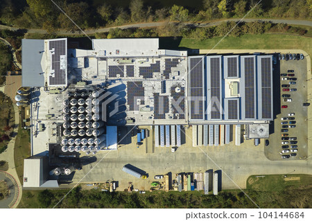 Aerial view of solar power plant with blue photovoltaic panels mounted on industrial building roof for producing green ecological electricity. Production of sustainable energy concept Aerial view of solar power plant with blue photovoltaic panels mounted on industrial building roof for producing green ecological electricity. Production of sustainable energy concept 104144684