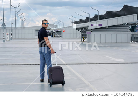 Businessman with a suitcase in an open parking lot at the airport. Business 104144783