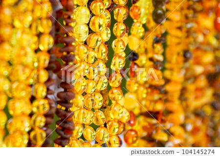 Amber beads background with many polished pieces of orange, yellow and brown amber Amber beads background with many polished pieces of orange, yellow and brown amber 104145274