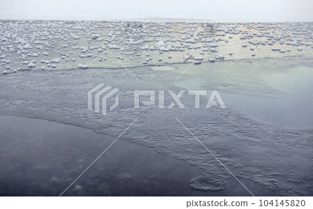 Ice on frozen lake / pond, small patches of snow on flat surface 104145820