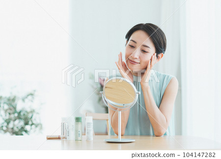 Middle-aged woman doing skin care in the living room Middle-aged woman doing skin care in the living room 104147282